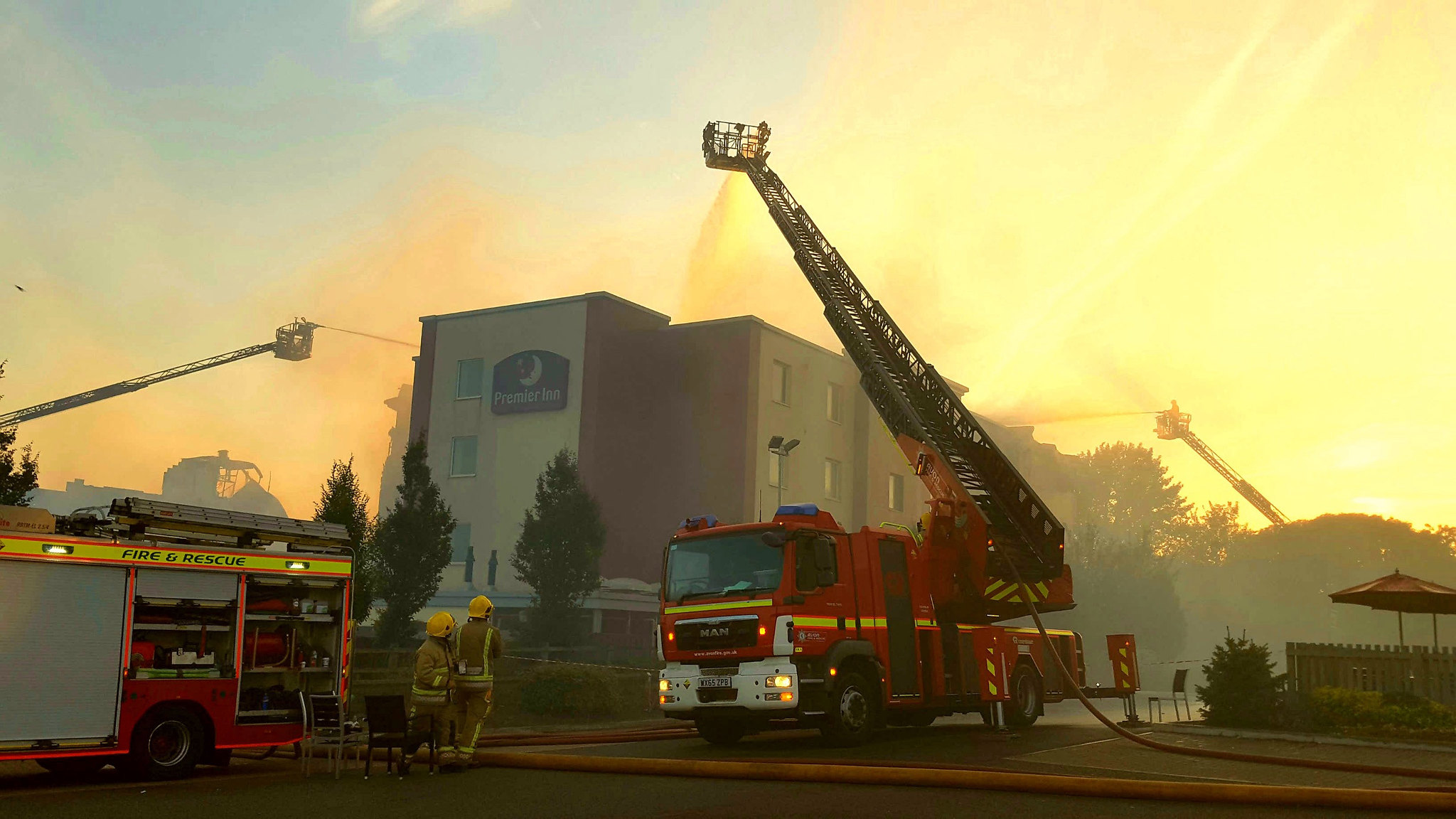 Firefighters beside smoking hotel 