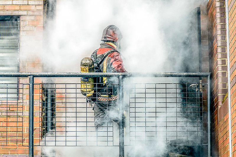 Firefighter in front of door with smoke coming out