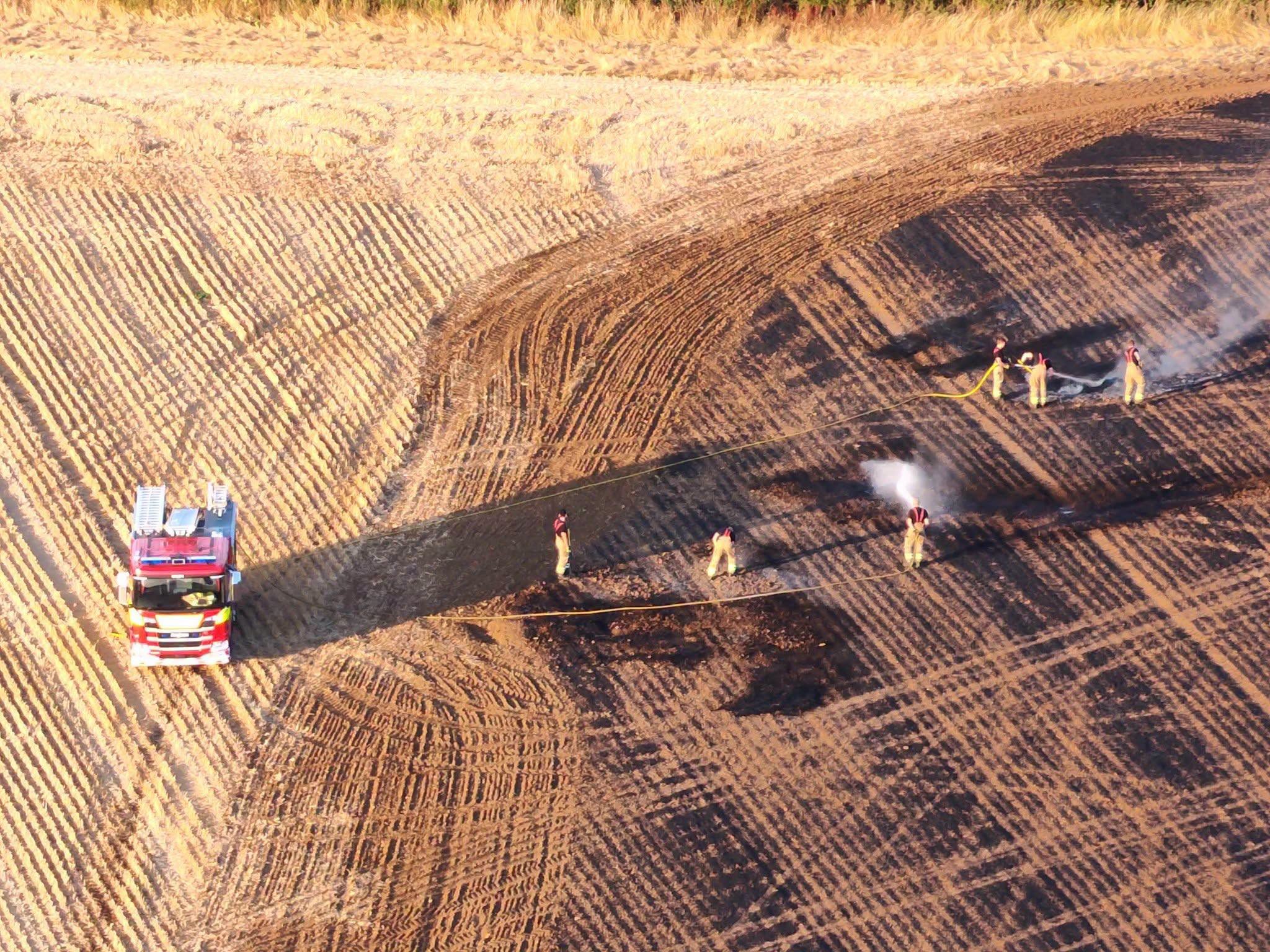 Firefighters manage a field wildfire