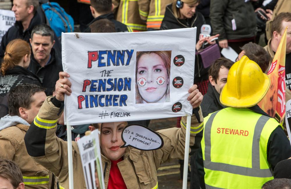 Firefighter holding sign that reads 'Penny Mordaunt penny pincher'