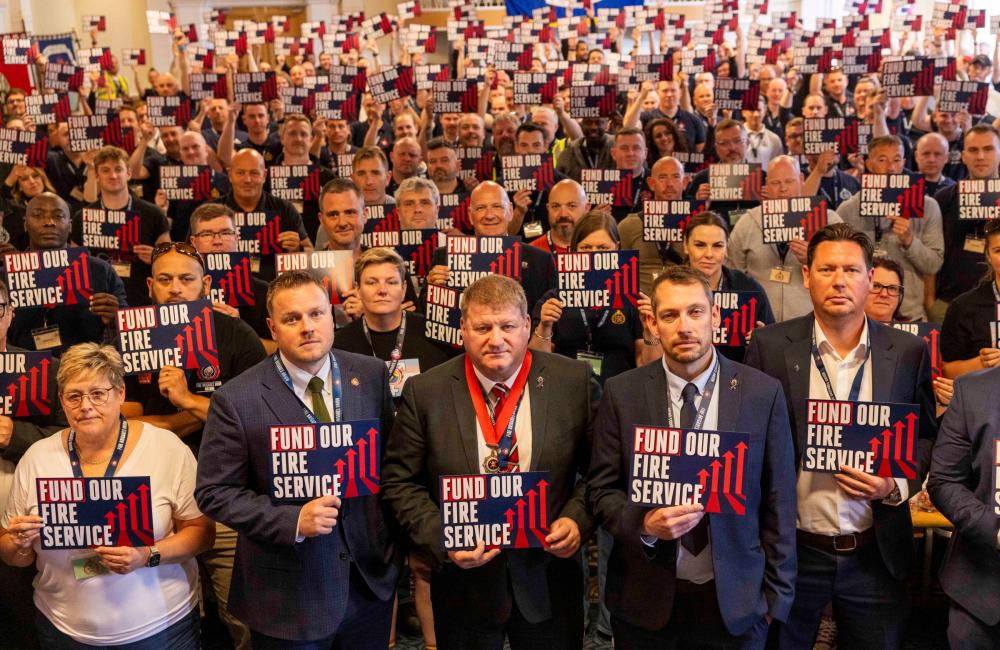 FBU conference 2025 delegates holding signs saying fund our fire service