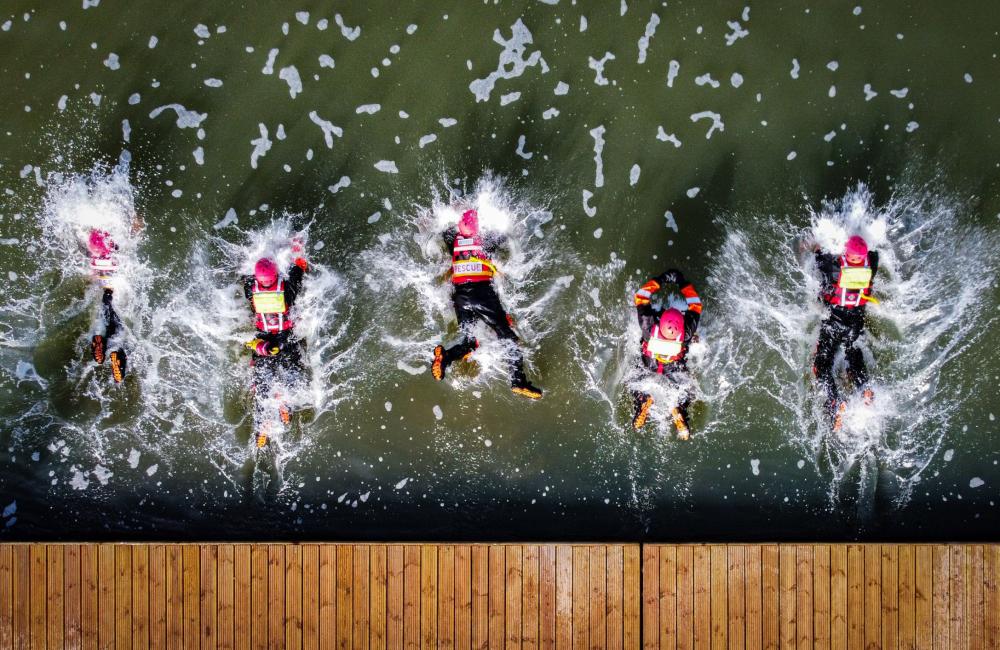 Firefighters jump into water from an aerial view