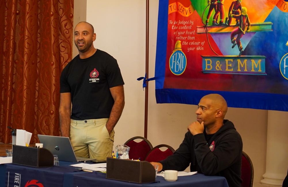 Adam McKenzie standing in front of an FBU banner at an event