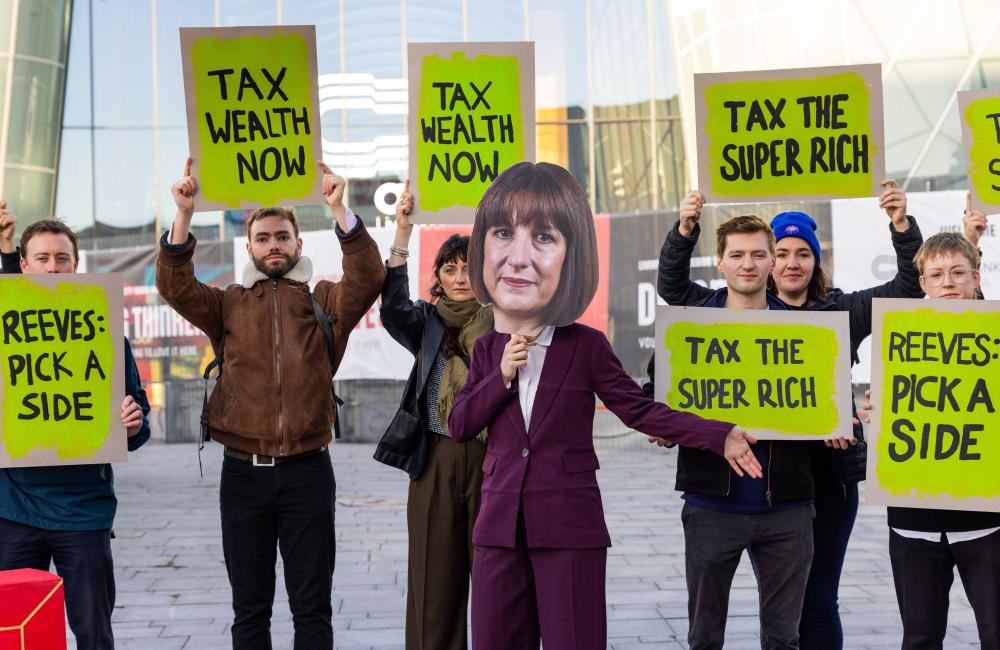 Protestors hold 'tax the rich signs', with one dressed as Rachel Reeves