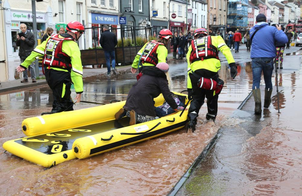 Firefighters drag a rescue boat across flood water
