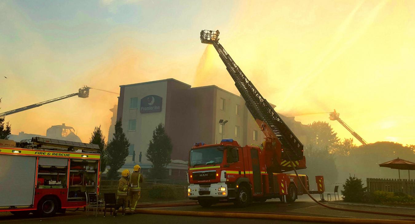 Firefighters beside smoking hotel 