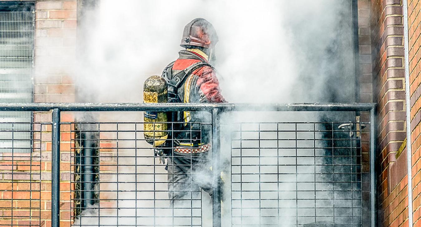 Firefighter in front of door with smoke coming out