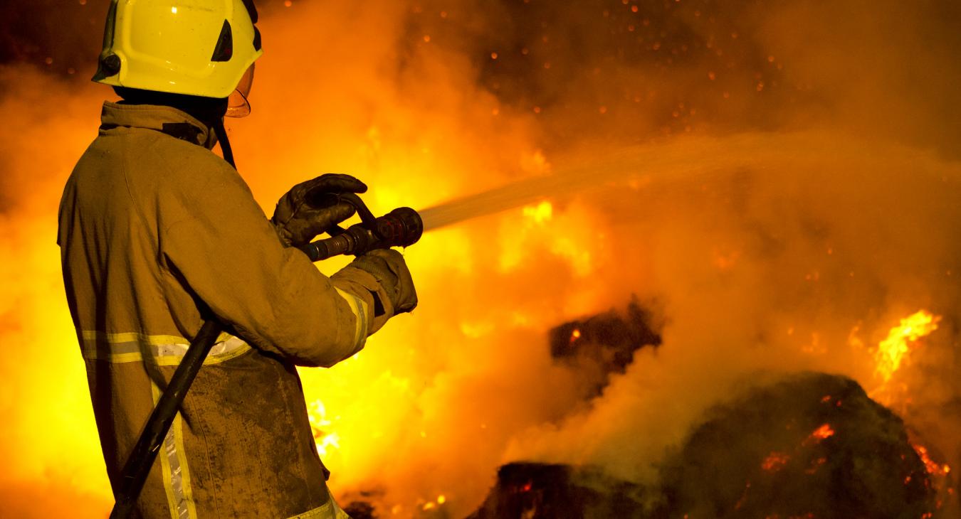 Firefighter pointing hose at fire