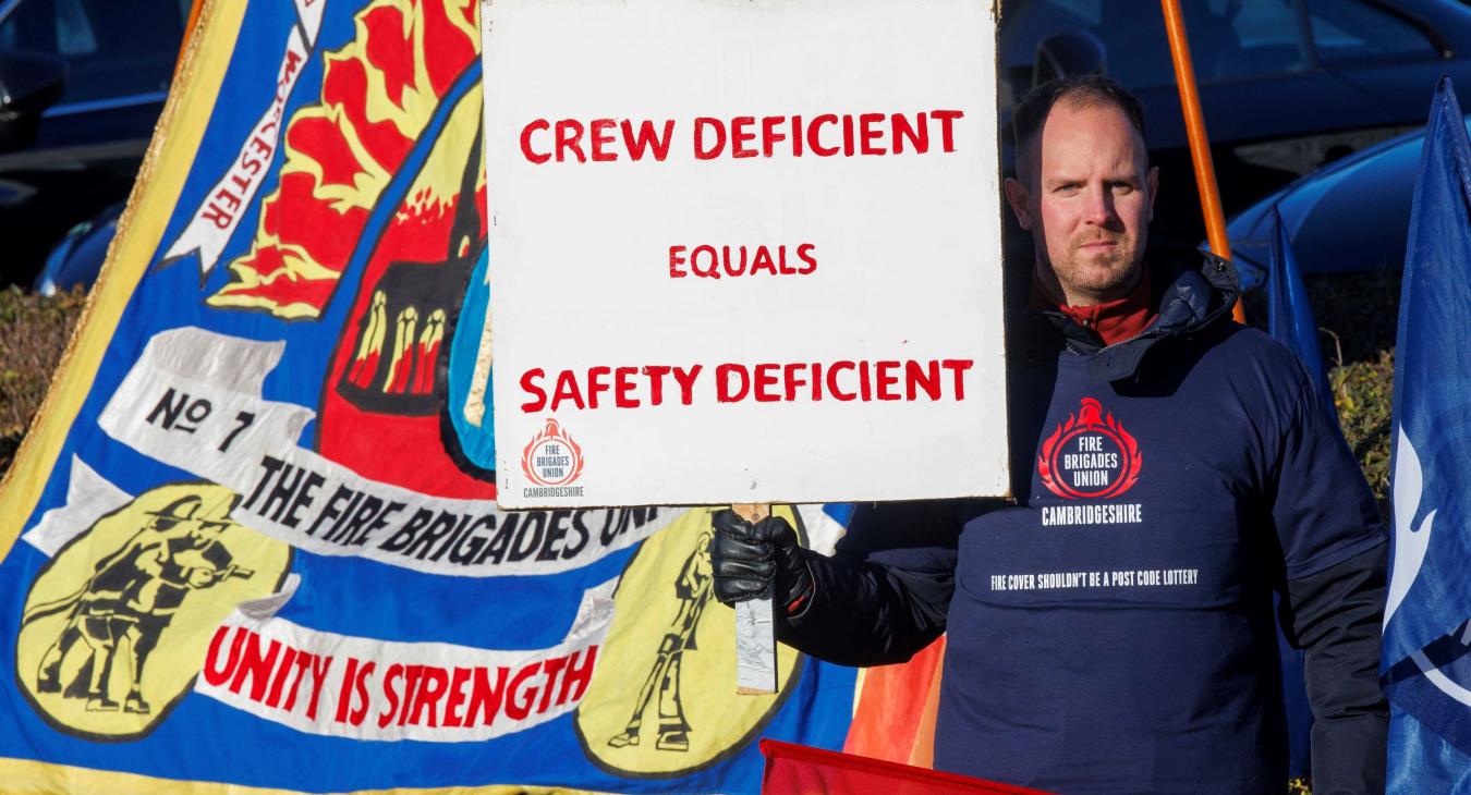 FBU member holds up a sign reading 'crew deficient equals safety deficient'