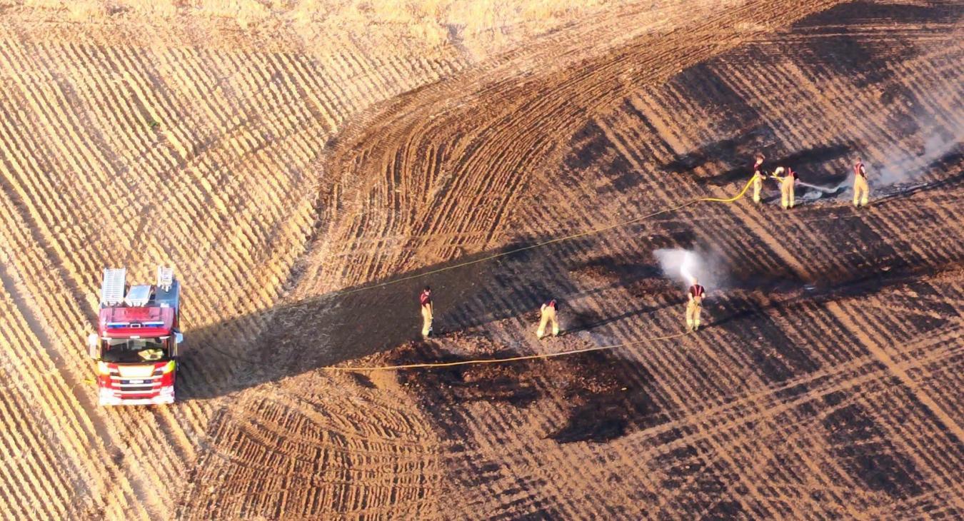 Firefighters manage a field wildfire