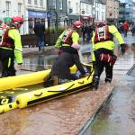 Firefighters drag a rescue boat across flood water